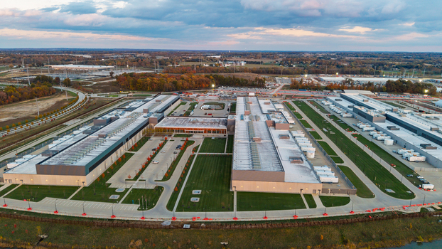 Aerial view of a large data center facility with expansive rooftops cooling units and parking areas surrounded by green lawns and autumn trees in New Albany Ohio United States. Aerial view of a large data center facility with expansive rooftops cooling units and parking areas surrounded by green lawns and autumn trees in New Albany Ohio United States.