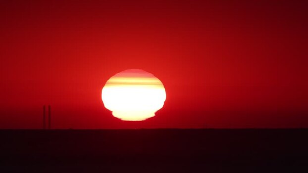 View of the red sunset over the sea with distant structures France.