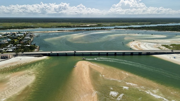 Aerial view of Matanzas Inlet featuring the bridge crossing the waterway sandy shoals coastal vegetation and turquoise waters in St. Johns County Florida United States. Aerial view of Matanzas Inlet featuring the bridge crossing the waterway sandy shoals coastal vegetation and turquoise waters in St. Johns County Florida United States.