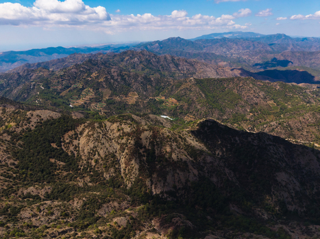 Aerial view of Kionia mountain range with rugged slopes dense green vegetation and rocky terrain under a bright blue sky in Lazanias Lefkosia Cyprus. Aerial view of Kionia mountain range with rugged slopes dense green vegetation and rocky terrain under a bright blue sky in Lazanias Lefkosia Cyprus.