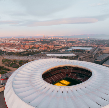 Aerial view of Riyadh Air Metropolitano Stadium with its distinctive white roof and green pitch set against the urban sprawl and skyline of Madrid Comunidad de Madrid Spain.