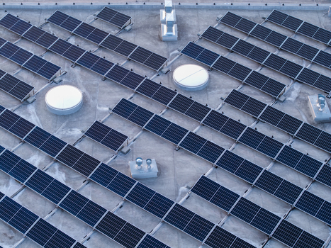 Aerial view of solar panels installed on a flat roof with circular skylights and ventilation units in Poland. Aerial view of solar panels installed on a flat roof with circular skylights and ventilation units in Poland.
