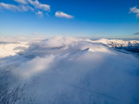 Aerial view of Babusar Pass covered in snow with thick clouds rolling over the mountain peaks under a blue sky Babusar KPK Pakistan. Aerial view of Babusar Pass covered in snow with thick clouds rolling over the mountain peaks under a blue sky Babusar KPK Pakistan.