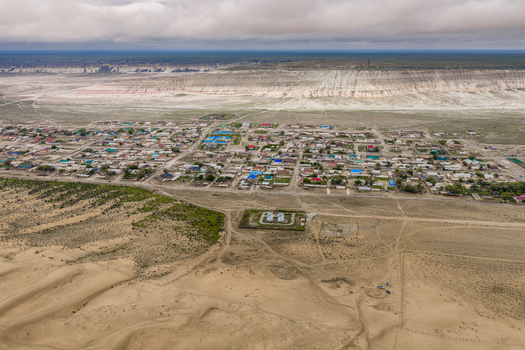 Aerial view of Senek village in the desert landscape of the Mangystau Region featuring sand dunes sparse vegetation and a distant plateau. Senek Mangystau Region Kazakhstan.