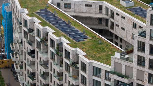 Aerial view of a modern residential building with a green roof and solar panels featuring brick facades and balconies along the Cruquiusweg in Amsterdam Noord Holland Netherlands.