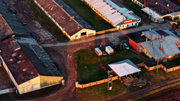 Aerial view of a farm complex with long industrial buildings dirt paths and agricultural equipment in Latvia. Aerial view of a farm complex with long industrial buildings dirt paths and agricultural equipment in Latvia.