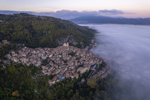 Aerial view of the historic hilltop town of Artena surrounded by dense forests and a sea of morning mist in Artena Lazio Italy.