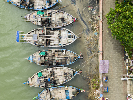 Aerial view of fishing boats moored along the coast near Jepara Floating Fish Market with vibrant turquoise accents contrasting with the weathered wood Jepara Central Java Indonesia.