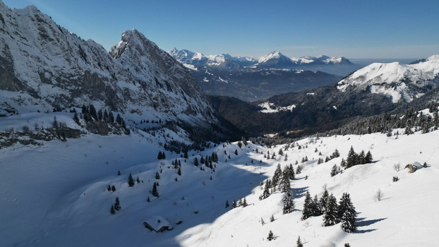 Aerial view of snow capped peaks cast long shadows over the valley the crisp white contrasting with the dark evergreens Samoëns Auvergne Rhône Alpes France. Aerial view of snow capped peaks cast long shadows over the valley the crisp white contrasting with the dark evergreens Samoëns Auvergne Rhône Alpes France.