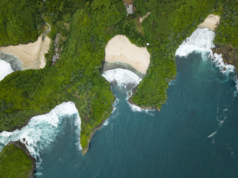 Aerial view of Sedahan Beach s vibrant green cliffs golden sands and white waves meeting the deep blue ocean Gunungkidul Regency Special Region of Yogyakarta Indonesia. Aerial view of Sedahan Beach s vibrant green cliffs golden sands and white waves meeting the deep blue ocean Gunungkidul Regency Special Region of Yogyakarta Indonesia.