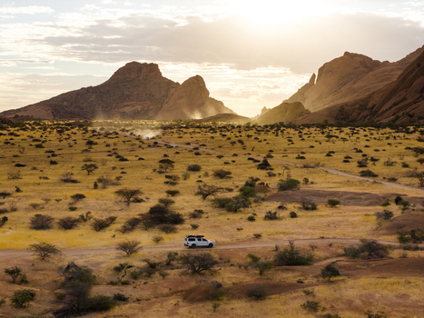 Aerial view of Spitzkoppe s granite peaks rise majestically from the vast golden savanna bathed in the warm ethereal glow of the setting sun Spitzkoppe Erongo Region Namibia. Aerial view of Spitzkoppe s granite peaks rise majestically from the vast golden savanna bathed in the warm ethereal glow of the setting sun Spitzkoppe Erongo Region Namibia.