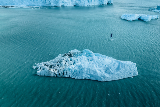 Aerial view of Perito Moreno Glacier with a windsurfer navigating past a large iceberg in the turquoise glacial waters in Perito Moreno Santa Cruz Province Argentina.