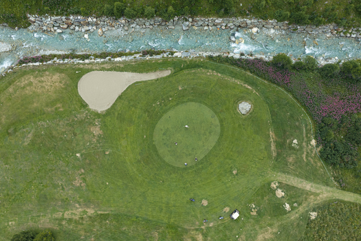 Aerial view of a golf course with a putting green sand bunkers and a mountain stream flowing through the alpine landscape in Breuil Cervinia Aosta Valley Italy. Aerial view of a golf course with a putting green sand bunkers and a mountain stream flowing through the alpine landscape in Breuil Cervinia Aosta Valley Italy.