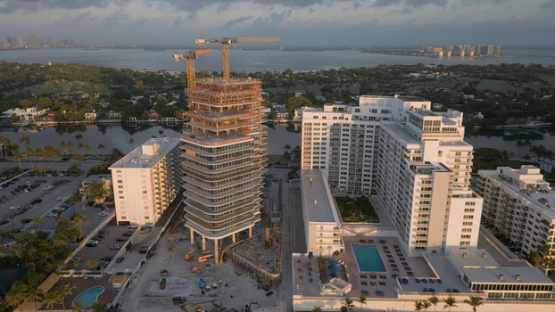 Aerial view of a high rise building under construction with cranes surrounded by residential apartment complexes and a swimming pool in Miami Beach Florida United States. Aerial view of a high rise building under construction with cranes surrounded by residential apartment complexes and a swimming pool in Miami Beach Florida United States.