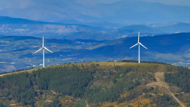 Aerial view of wind turbines standing on a green hill covered with trees in the rolling landscape of Lisbon Lisbon Portugal. Aerial view of wind turbines standing on a green hill covered with trees in the rolling landscape of Lisbon Lisbon Portugal.