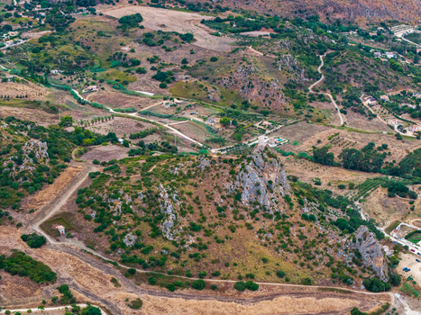 Aerial view of rugged arid hills and rocky outcrops in the Sicilian countryside featuring winding dirt paths sparse vegetation and rural structures in Palermo Sicily Italy. Aerial view of rugged arid hills and rocky outcrops in the Sicilian countryside featuring winding dirt paths sparse vegetation and rural structures in Palermo Sicily Italy.