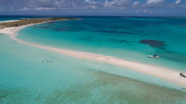Aerial view of the sandbar in Los Roques archipelago surrounded by turquoise waters with a boat and people swimming near the white sand in Los Roques Dependencias Federales Venezuela. Aerial view of the sandbar in Los Roques archipelago surrounded by turquoise waters with a boat and people swimming near the white sand in Los Roques Dependencias Federales Venezuela.