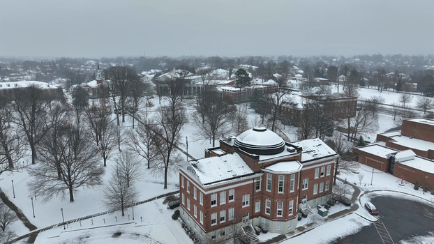 Aerial view of the snow covered campus featuring historic brick buildings and a prominent domed structure amidst bare trees under a winter sky in Lynchburg Virginia United States.