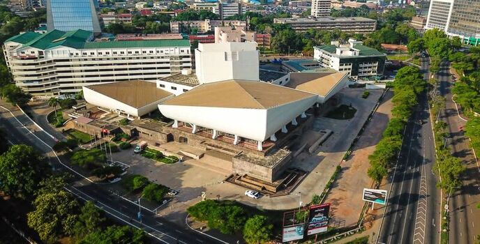 Aerial view of the National Theatre of Ghana with its distinctive white roof structure surrounded by urban roads green trees and modern buildings in Ghana. Aerial view of the National Theatre of Ghana with its distinctive white roof structure surrounded by urban roads green trees and modern buildings in Ghana.