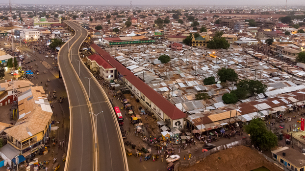 Aerial view of the Tamale Interchange winding through the dense urban landscape with corrugated metal rooftops and busy streets in Tamale Northern Region Ghana.