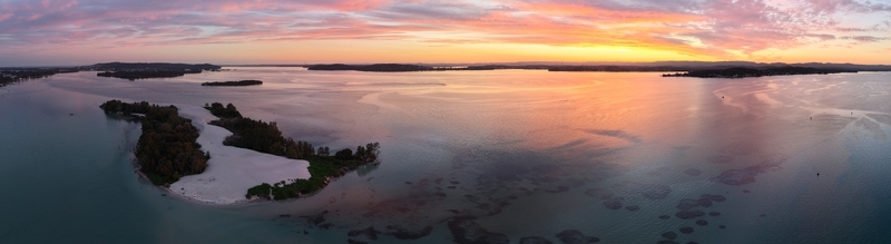 Aerial view of islands stand as silent witnesses to the dawn s embrace where the sky s fiery hues meet the tranquil waters Newcastle New South Wales Australia.