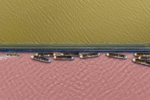 Aerial view of boats floating on the pink waters contrasting sharply with the yellow waters separated by a thin strip of land San Pedro del Pinatar Region of Murcia Spain. Aerial view of boats floating on the pink waters contrasting sharply with the yellow waters separated by a thin strip of land San Pedro del Pinatar Region of Murcia Spain.