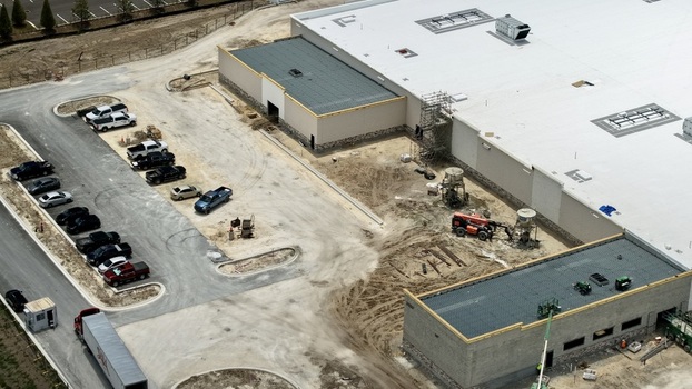 Aerial view of the Foundry Lane construction site featuring a large commercial building with white roofing machinery and parked vehicles World Golf Village Florida United States.