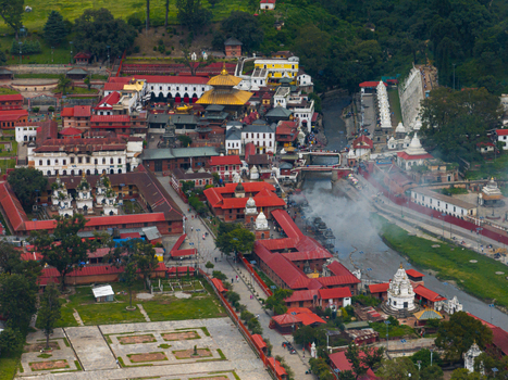 Aerial view of Pashupatinath Temple complex with its iconic golden roof historic red tiled buildings and the Bagmati River flowing through the sacred site in Kathmandu Nepal.