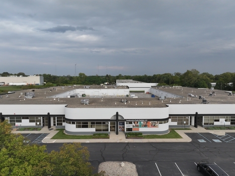 Aerial view of a modern commercial building with a flat roof and parking lot surrounded by trees in Indianapolis Indiana United States. Aerial view of a modern commercial building with a flat roof and parking lot surrounded by trees in Indianapolis Indiana United States.