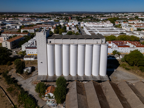 Aerial view of a large white grain silo complex surrounded by urban buildings and industrial structures in Evora Evora District Portugal. Aerial view of a large white grain silo complex surrounded by urban buildings and industrial structures in Evora Evora District Portugal.