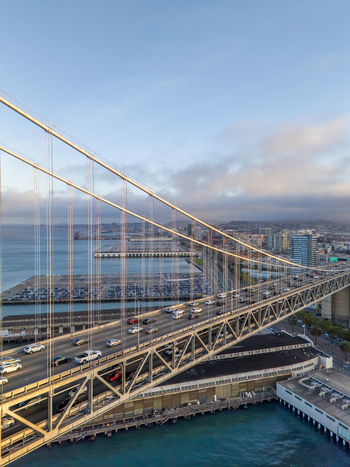 Aerial view of the San Francisco oakland bay bridge with traffic waterfront piers and city skyline in the background San Francisco California United States. Aerial view of the San Francisco oakland bay bridge with traffic waterfront piers and city skyline in the background San Francisco California United States.