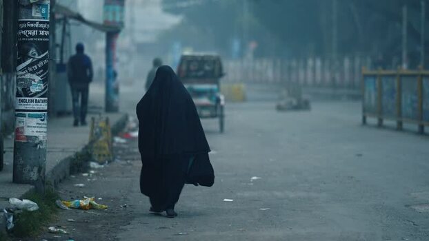 View of a woman in a burqa walking on a misty street Bangladesh. View of a woman in a burqa walking on a misty street Bangladesh.