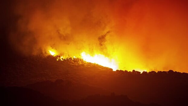 View of a forest fire burning on a hillside in Spain.