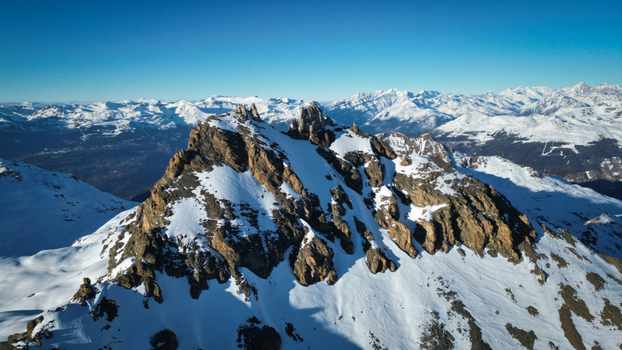Aerial view of the rugged snow dusted Becs de Bosson peak piercing the crisp blue sky a stark contrast to the surrounding white mountain range Anniviers Valais Switzerland. Aerial view of the rugged snow dusted Becs de Bosson peak piercing the crisp blue sky a stark contrast to the surrounding white mountain range Anniviers Valais Switzerland.