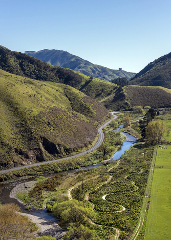 Aerial view of restored wetlands with a winding stream lush green hills and a road running through the valley in Cable Bay Nelson Region New Zealand. Aerial view of restored wetlands with a winding stream lush green hills and a road running through the valley in Cable Bay Nelson Region New Zealand.