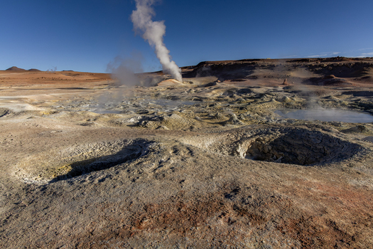 View of Geisers Sol de la Manana with geothermal steam vents bubbling mud pools and volcanic terrain under a clear blue sky in Sur Lipez Potosi Department Bolivia. View of Geisers Sol de la Manana with geothermal steam vents bubbling mud pools and volcanic terrain under a clear blue sky in Sur Lipez Potosi Department Bolivia.