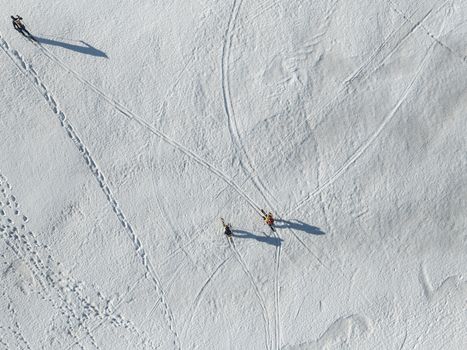 Aerial view of skiers with long shadows on the snowy Mount Etna south slope with tracks and footprints Nicolosi Sicilia Italy. Aerial view of skiers with long shadows on the snowy Mount Etna south slope with tracks and footprints Nicolosi Sicilia Italy.