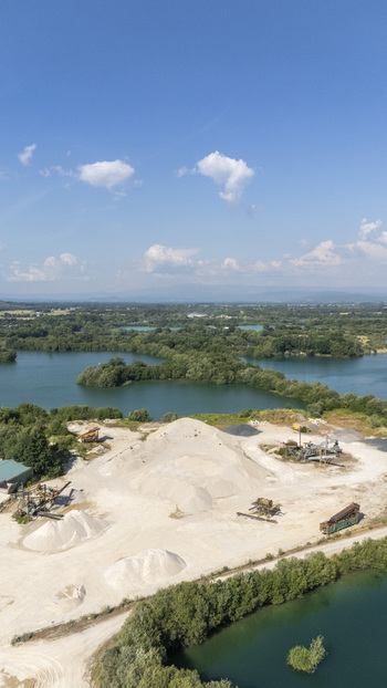 Aerial view of Extraccion de aridos Lima S.L gravel extraction site with sand piles and industrial machinery near water bodies in Vilarino das Poldras Ourense Spain. Aerial view of Extraccion de aridos Lima S.L gravel extraction site with sand piles and industrial machinery near water bodies in Vilarino das Poldras Ourense Spain.