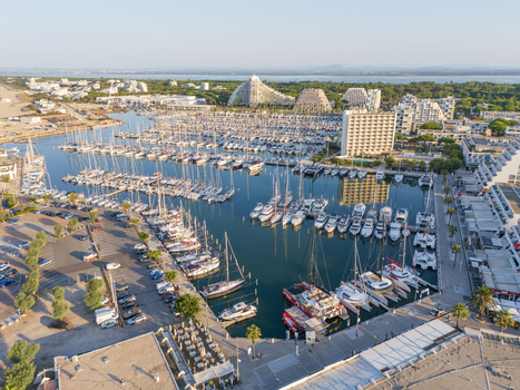 Aerial view of the marina in La Grande Motte with numerous sailboats and yachts moored in calm waters surrounded by distinctive pyramid shaped architecture. La Grande Motte Occitanie France.