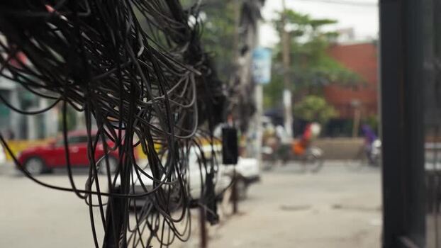 View of tangled overhead power cables on a busy street Bangladesh.
