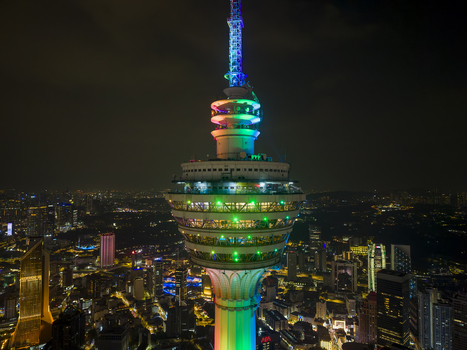 Kuala Lumpur Malaysia 11 March 2026 Aerial view of Menara Kuala Lumpur tower illuminated with vibrant rainbow colors against the dark night city skyline.