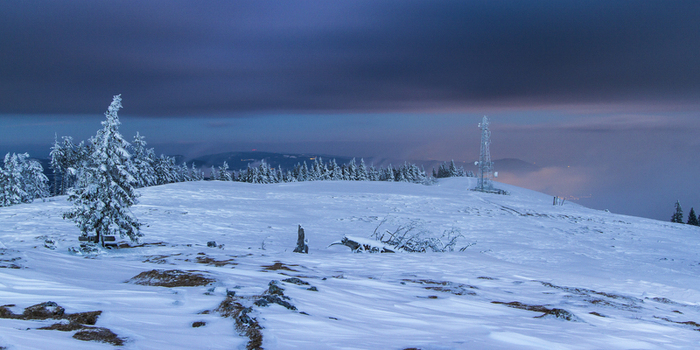 View of a snow covered landscape with frosted trees and a telecommunications tower under a twilight sky Schöckl Styria Austria. View of a snow covered landscape with frosted trees and a telecommunications tower under a twilight sky Schöckl Styria Austria.