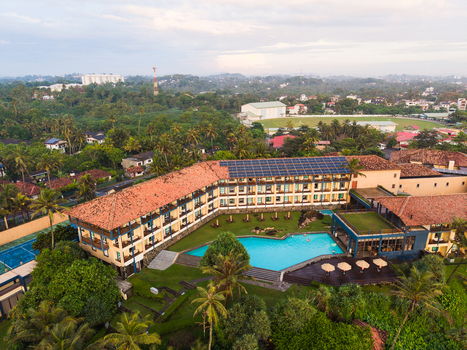 Aerial view of a modern resort hotel with a turquoise swimming pool solar panels and terracotta rooftops surrounded by palm trees in Galle Southern Province Sri Lanka. Aerial view of a modern resort hotel with a turquoise swimming pool solar panels and terracotta rooftops surrounded by palm trees in Galle Southern Province Sri Lanka.