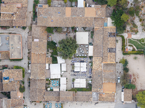 Aerial view of a central courtyard with restaurant tables and umbrellas surrounded by historic stone buildings in San Vito Lo Capo Sicilia Italy. Aerial view of a central courtyard with restaurant tables and umbrellas surrounded by historic stone buildings in San Vito Lo Capo Sicilia Italy.