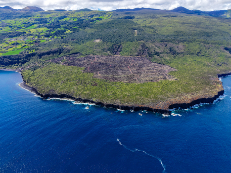 Aerial view of a dramatic coastline where dark volcanic rock meets the deep blue sea bordered by lush green forests Prainha Pico Azores Portugal. Aerial view of a dramatic coastline where dark volcanic rock meets the deep blue sea bordered by lush green forests Prainha Pico Azores Portugal.