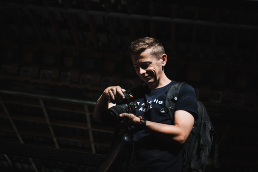 Aerial view of a photographer reviewing images on his camera illuminated by a shaft of light location omitted.