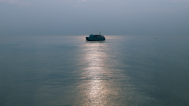 Aerial view of a ferry boat sailing on the calm sea with sunlight reflecting on the water in Dumaguete City Negros Island Region Philippines. Aerial view of a ferry boat sailing on the calm sea with sunlight reflecting on the water in Dumaguete City Negros Island Region Philippines.