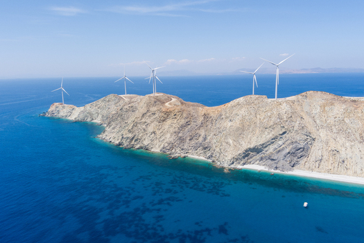 Greece 21 September 2026 Aerial view of wind turbines situated on a rugged coastal cliff overlooking the deep blue Aegean Sea under a clear sky. Greece 21 September 2026 Aerial view of wind turbines situated on a rugged coastal cliff overlooking the deep blue Aegean Sea under a clear sky.