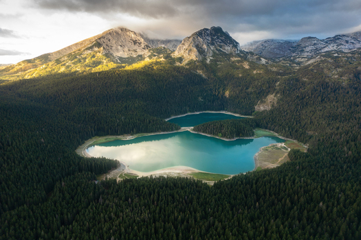 Aerial view of Crno Jezero surrounded by dense pine forests and the dramatic peaks of Durmitor National Park in Zabljak Zabljak Municipality Montenegro. Aerial view of Crno Jezero surrounded by dense pine forests and the dramatic peaks of Durmitor National Park in Zabljak Zabljak Municipality Montenegro.