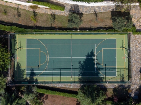 Aerial view of a multi purpose sports court with green surface and yellow markings surrounded by trees and stone pathways in a residential area in Istanbul Istanbul Turkiye. Aerial view of a multi purpose sports court with green surface and yellow markings surrounded by trees and stone pathways in a residential area in Istanbul Istanbul Turkiye.